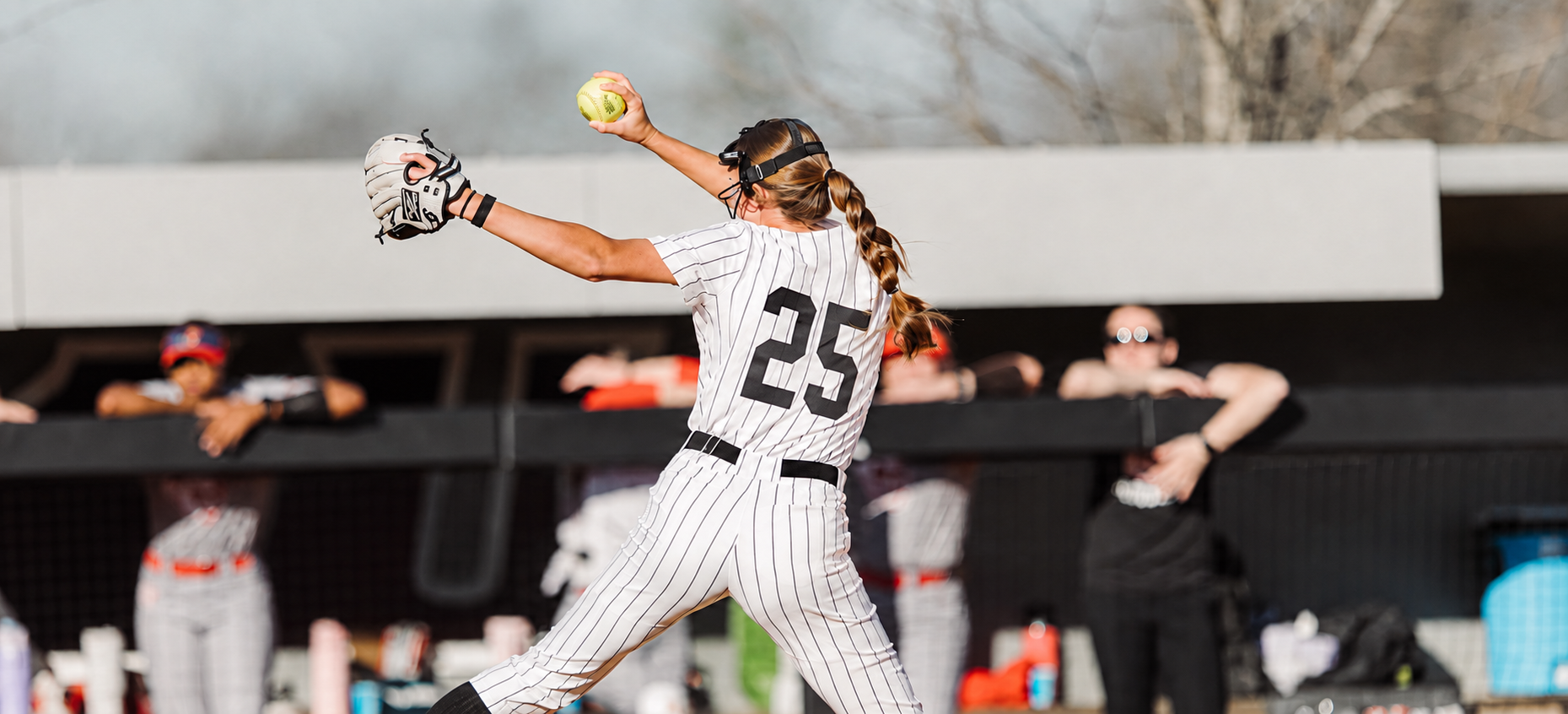 Softball pitcher in pinstripes releasing a pitch